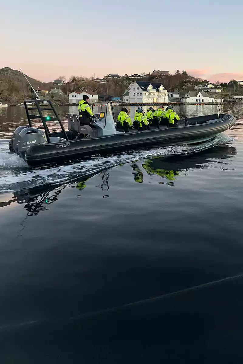 RIB-båt med passasjerer på rolig sjø i Bergen ved solnedgang